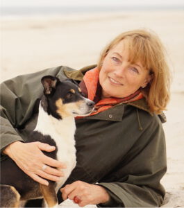 Foto von Annette Dragun mit Hund Bodo am Strand.